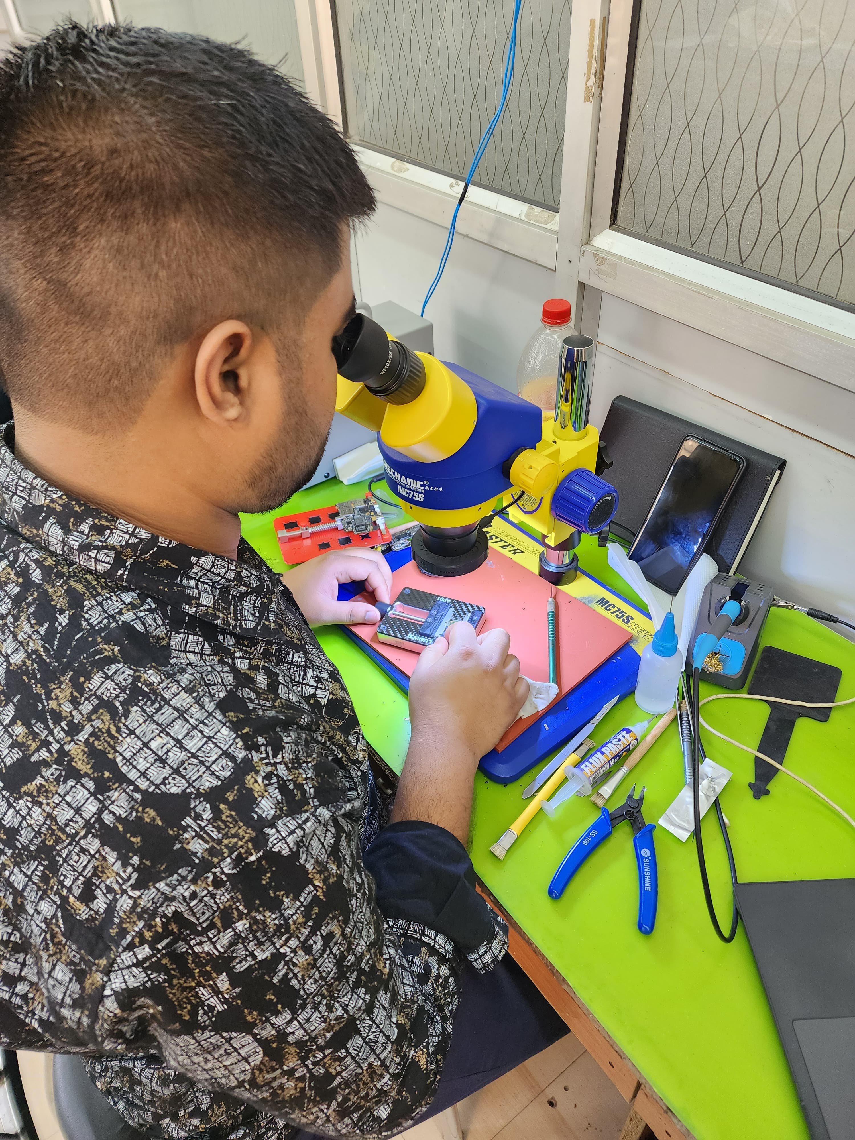 Student doing practical chip-level repair under a microscope